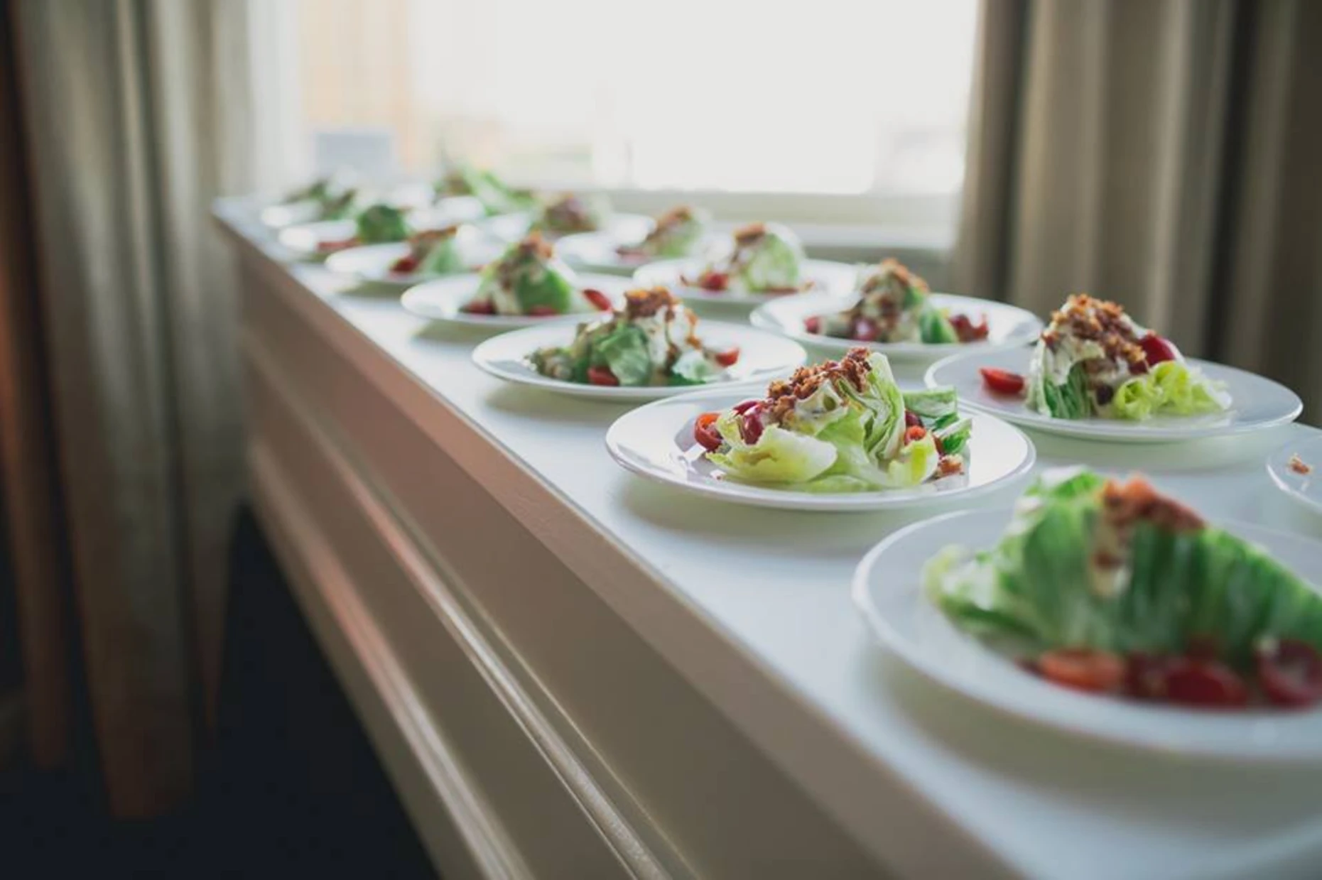 Plated wedge salads lined up for a wedding reception